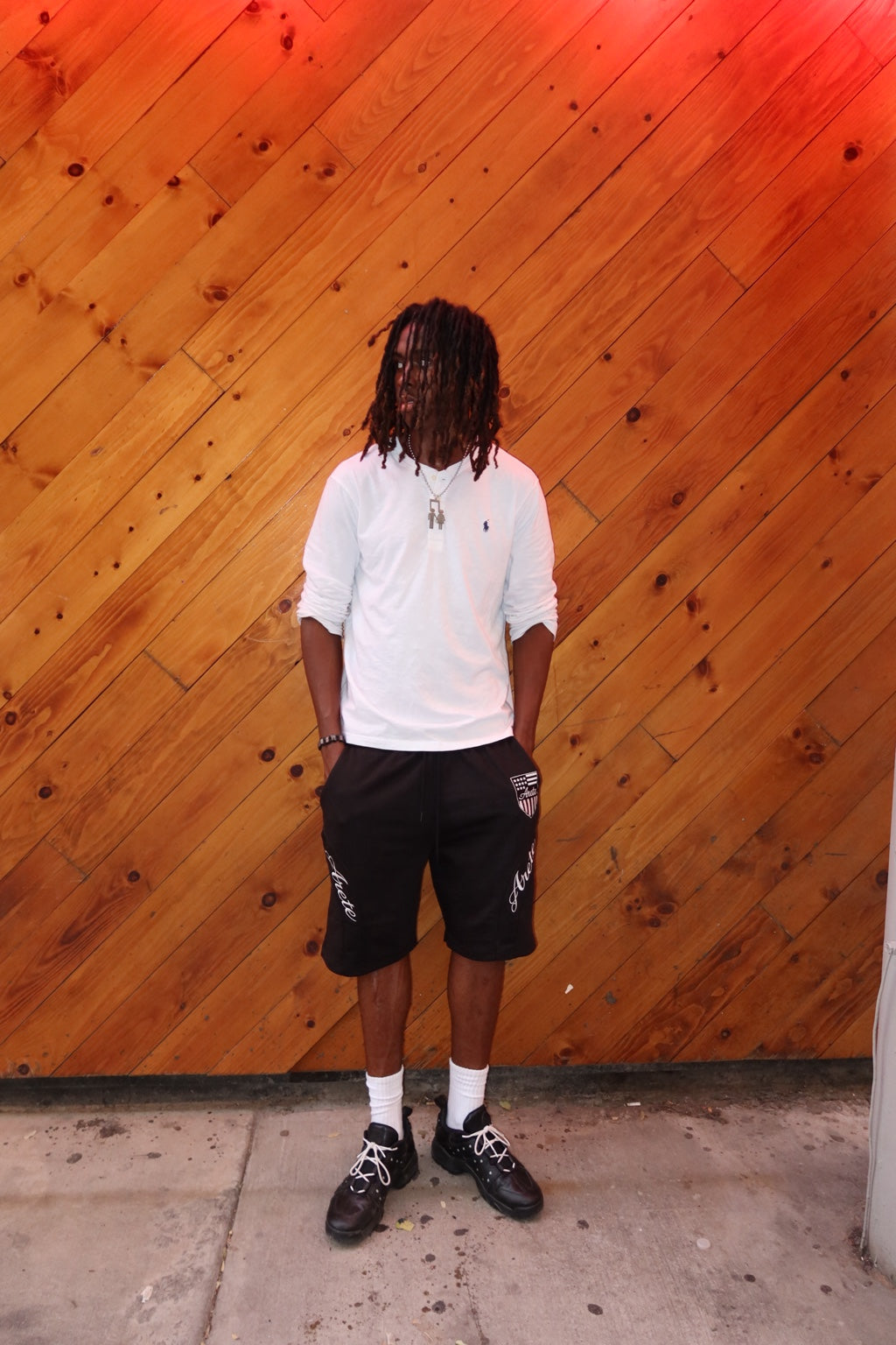 Model wearing black ARETE shorts in front of a wood wall